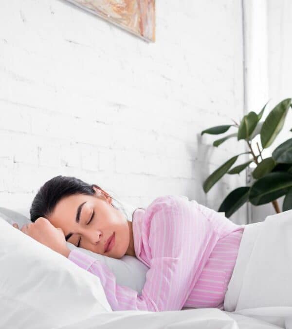 A woman sleeping in a bed with white pillows.