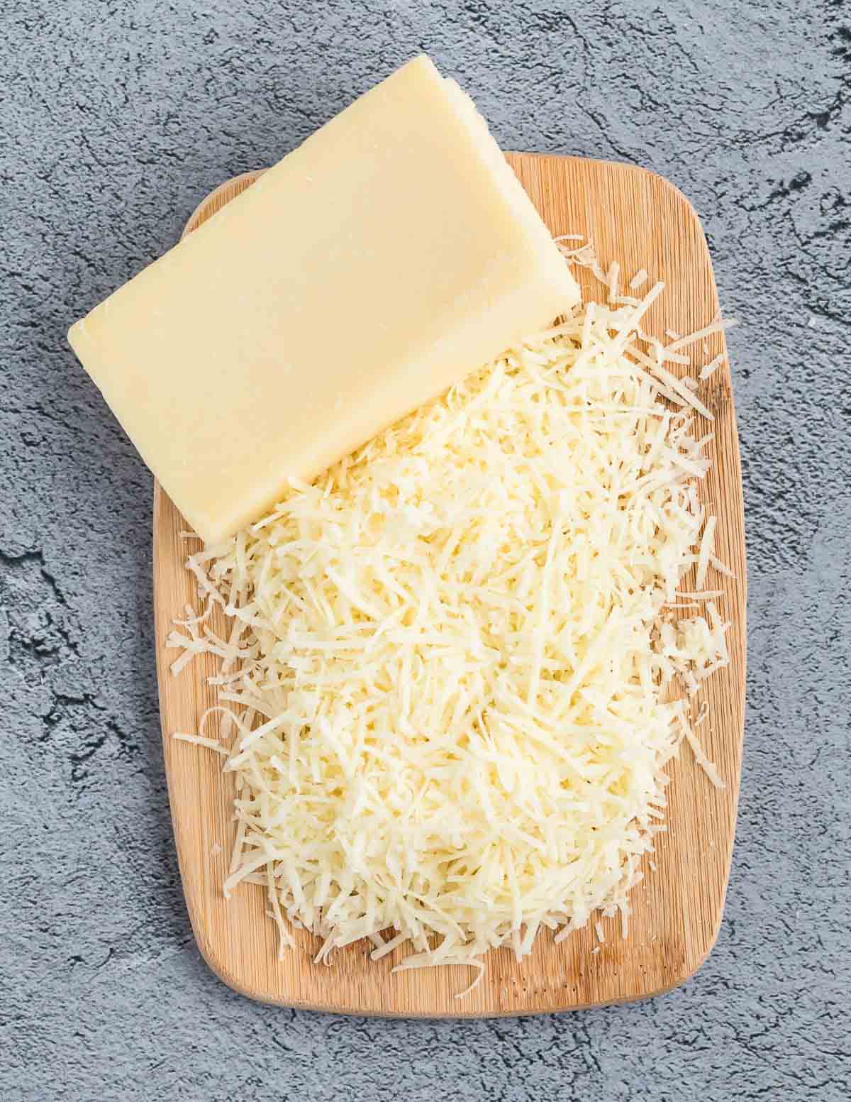 Shredded parmesan cheese on a wooden cutting board.