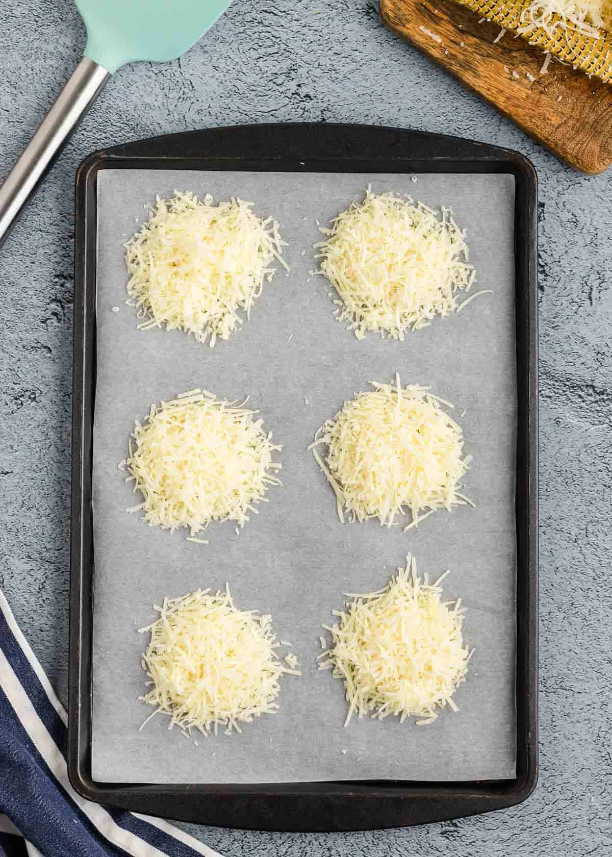 Grated cheese on a baking sheet in piles.