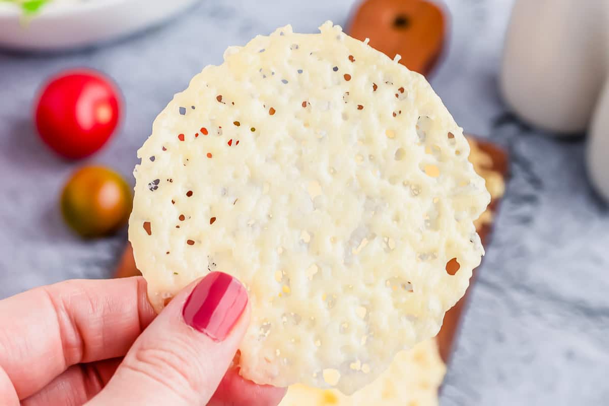 A person holding a parmesan crisp in their hand.