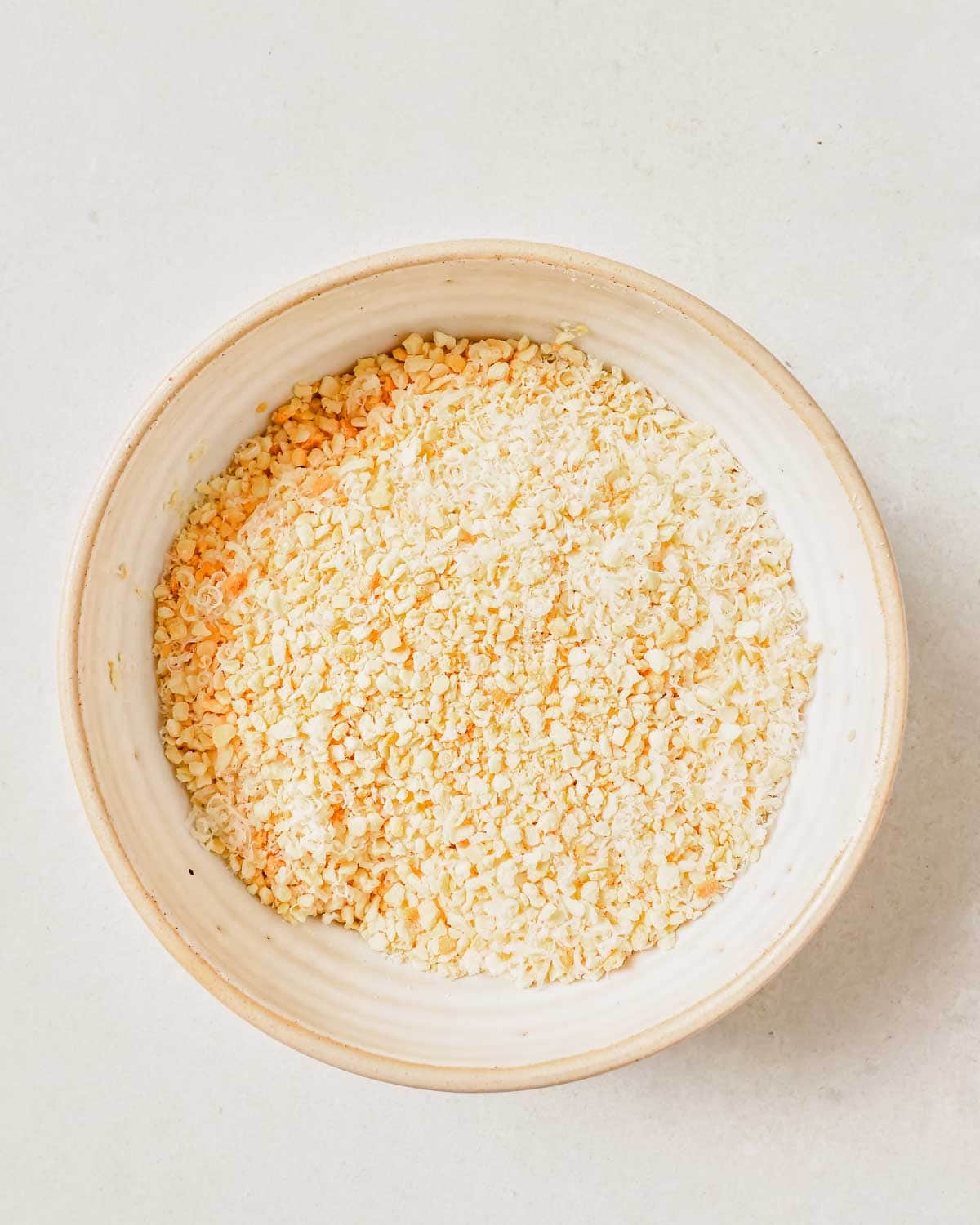 A bowl of breadcrumbs on a white surface.