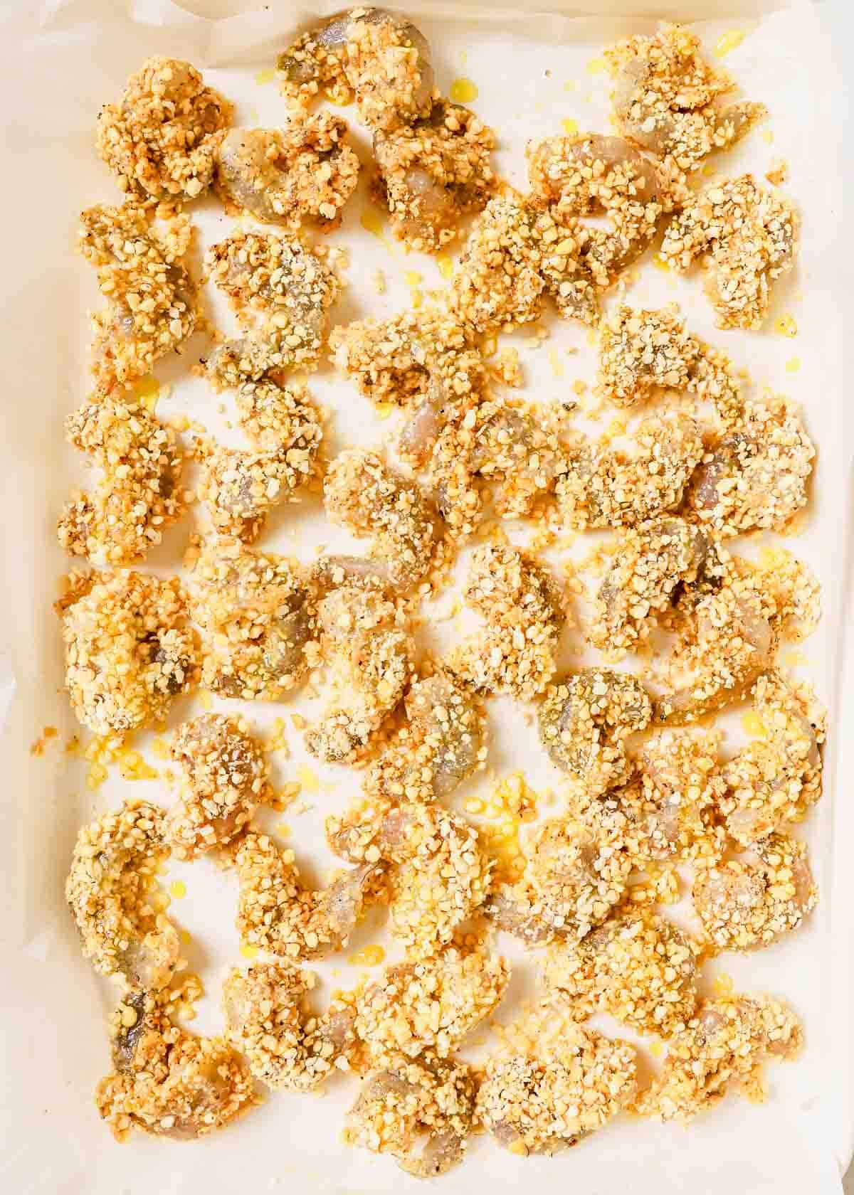 A baking sheet with shrimp coated in a breadcrumb mixture.