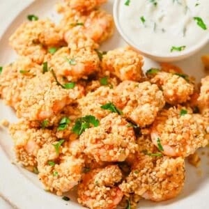 A plate of popcorn shrimp with a dipping sauce.