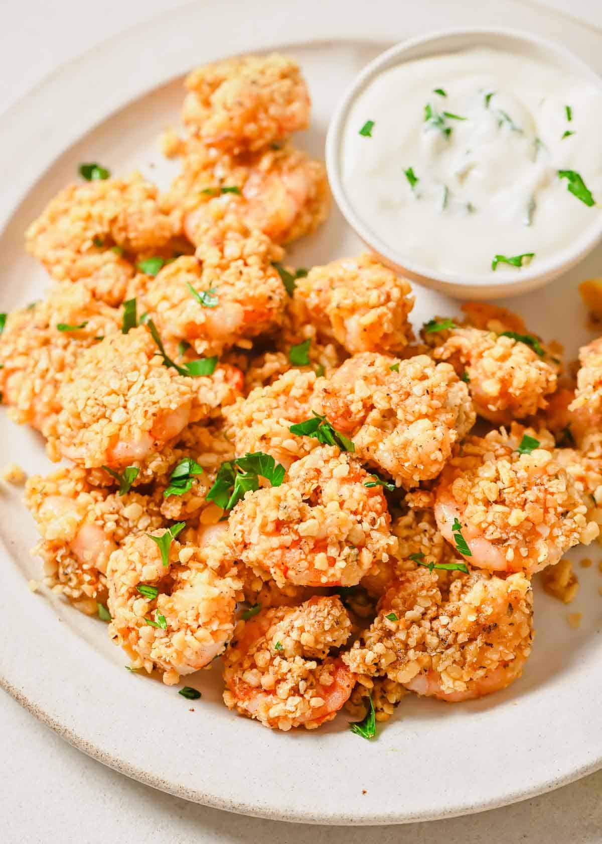 A plate of popcorn shrimp with a dipping sauce.