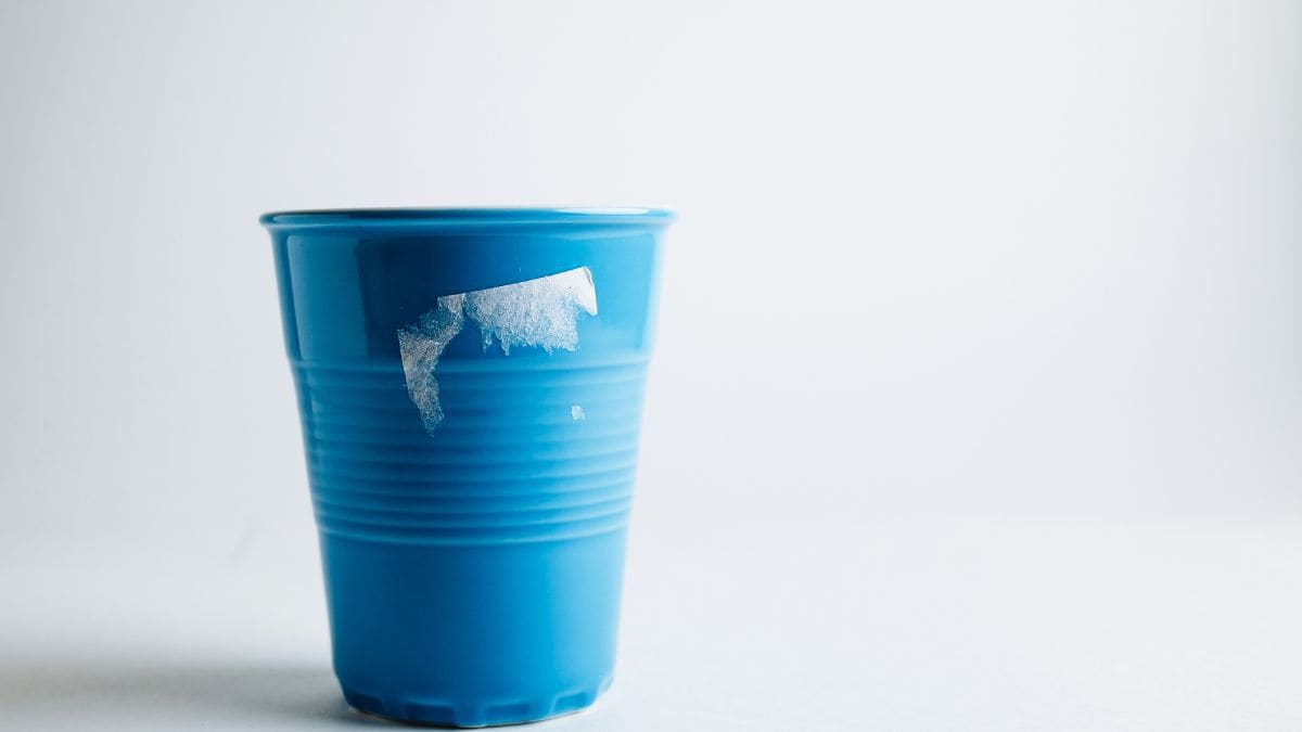 Blue plastic cup with a torn label on a white background.