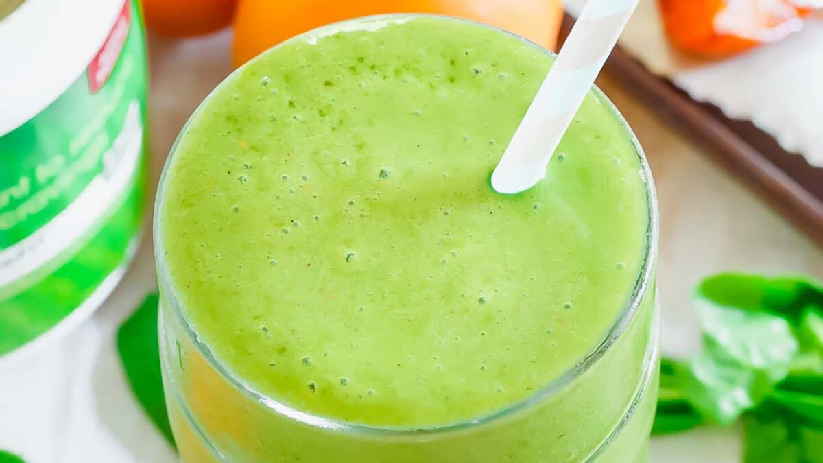 A green smoothie with a straw and apricots.