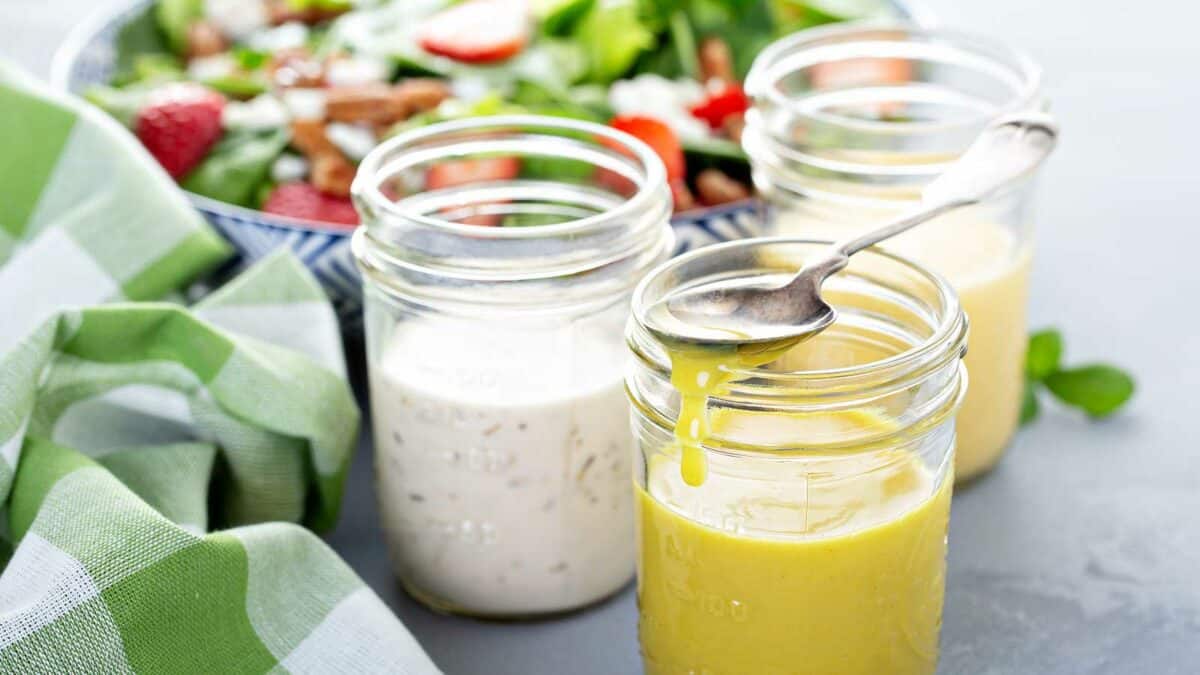 A spoon in a jar with different dressings.