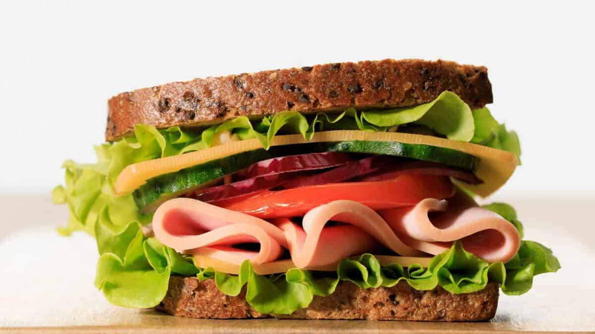 A ham and cheese sandwich on a wooden board.