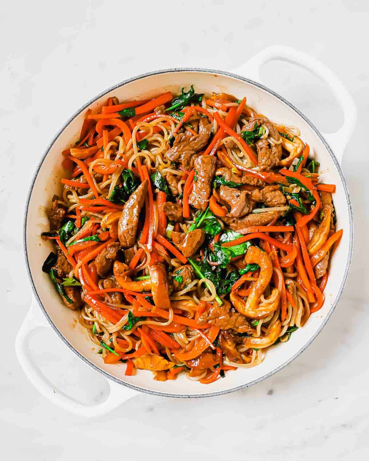 A pan full of noodles with meat and vegetables.