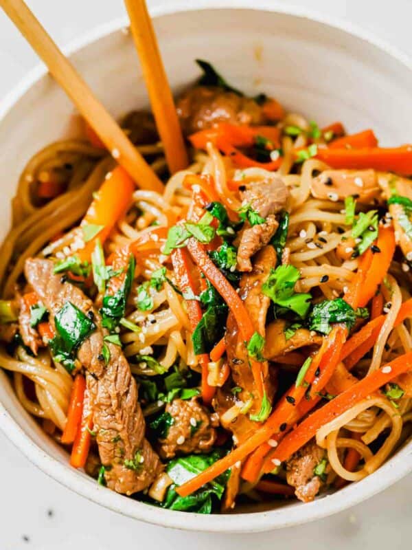 A bowl of sweet potato glass noodles with beef and vegetables.