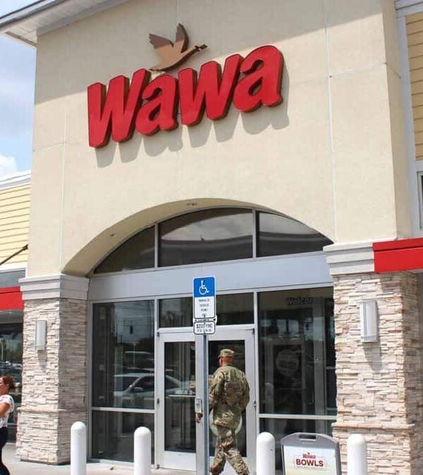 A soldier walking past a store front.