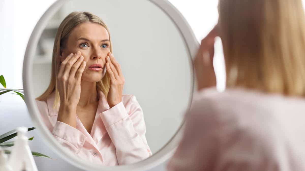 Woman examining her face in the mirror.