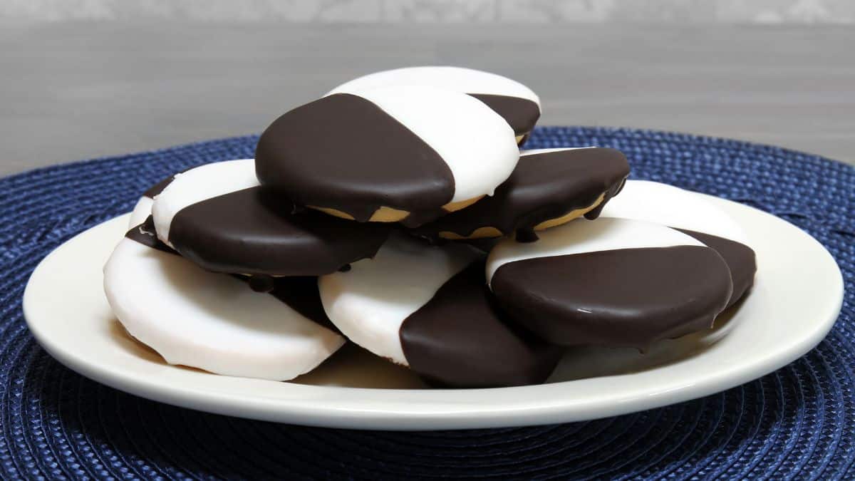 A plate of black and white cookies on a blue woven placemat.