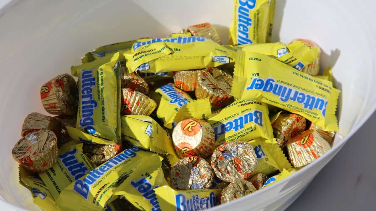 A bowl filled with an assortment of individually wrapped raffaello and butterfinger candies.