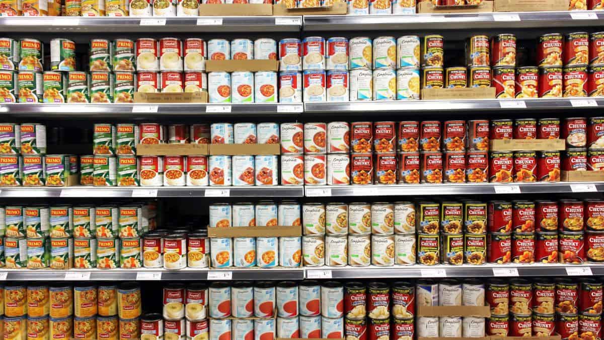 A variety of canned food products neatly organized on supermarket shelves.