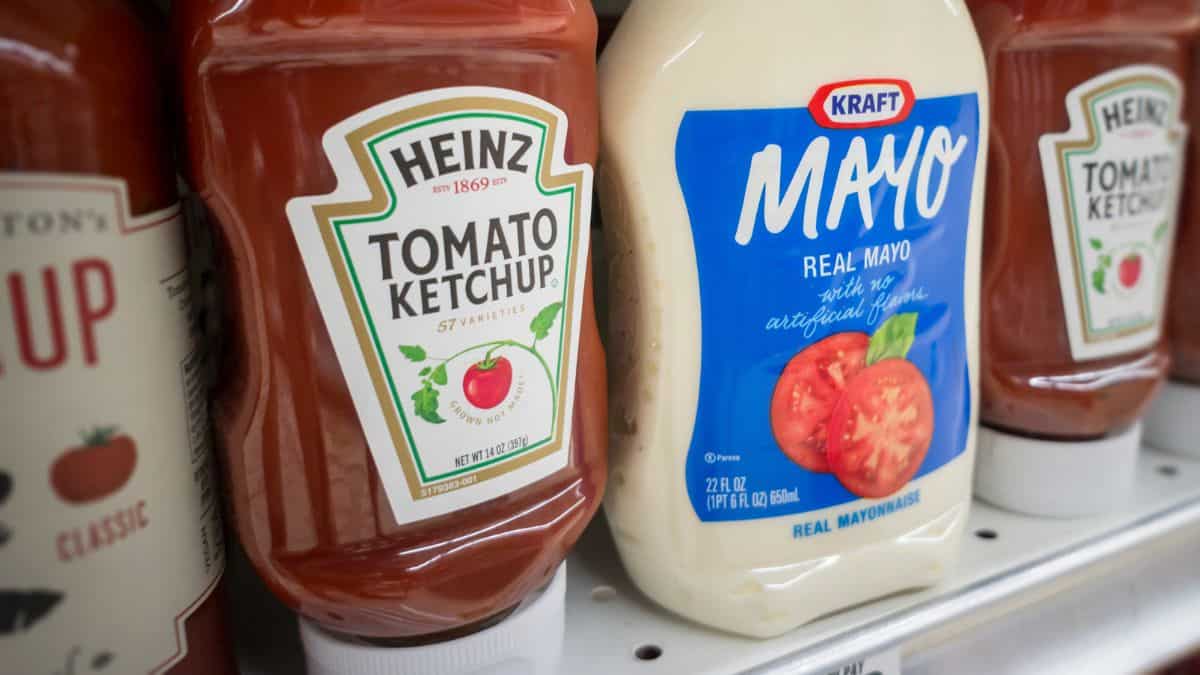 Bottles of heinz tomato ketchup and kraft mayo on a grocery store shelf.