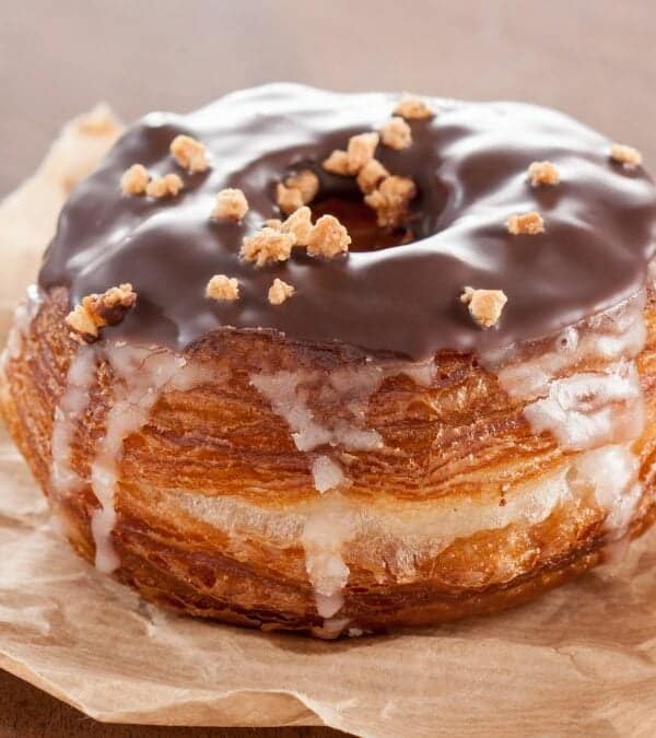 A chocolate-glazed, crumble-topped pastry, iconic among New York City foods, on a piece of parchment paper.