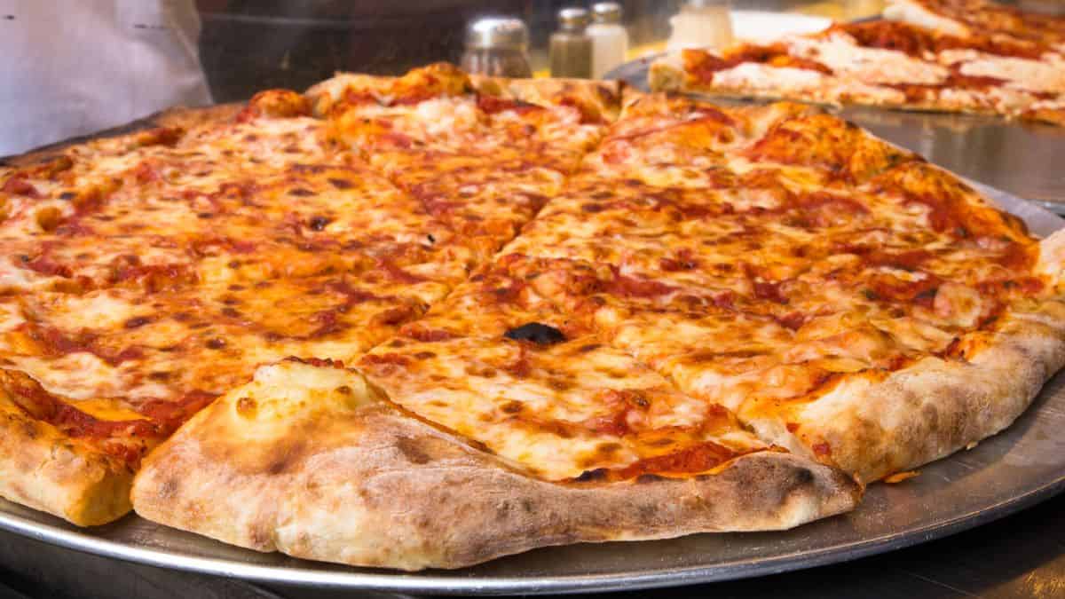 A large cheese pizza on a metal tray with a golden crust and melted cheese.
