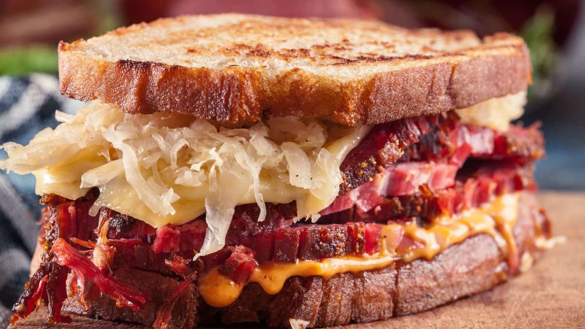 Grilled pastrami sandwich with sauerkraut and melted cheese on rye bread.