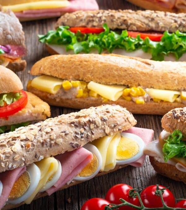 Assorted fresh sandwiches with various fillings on a wooden table.