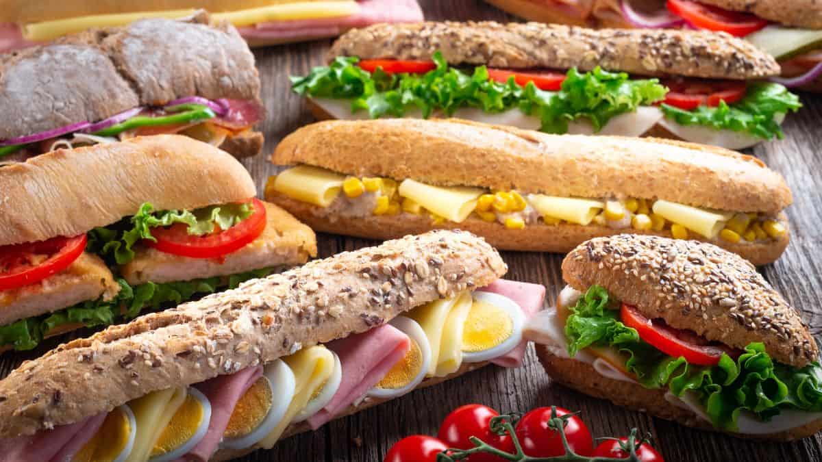 Assorted fresh sandwiches with various fillings on a wooden table.
