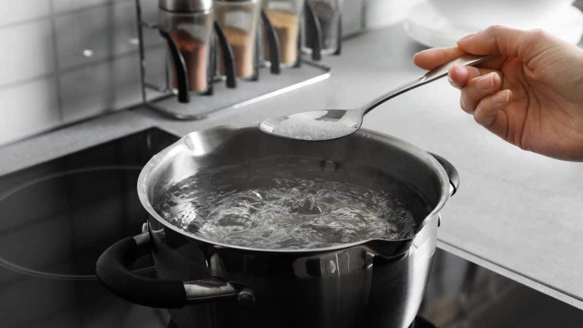 Adding salt to boiling water in a kitchen.