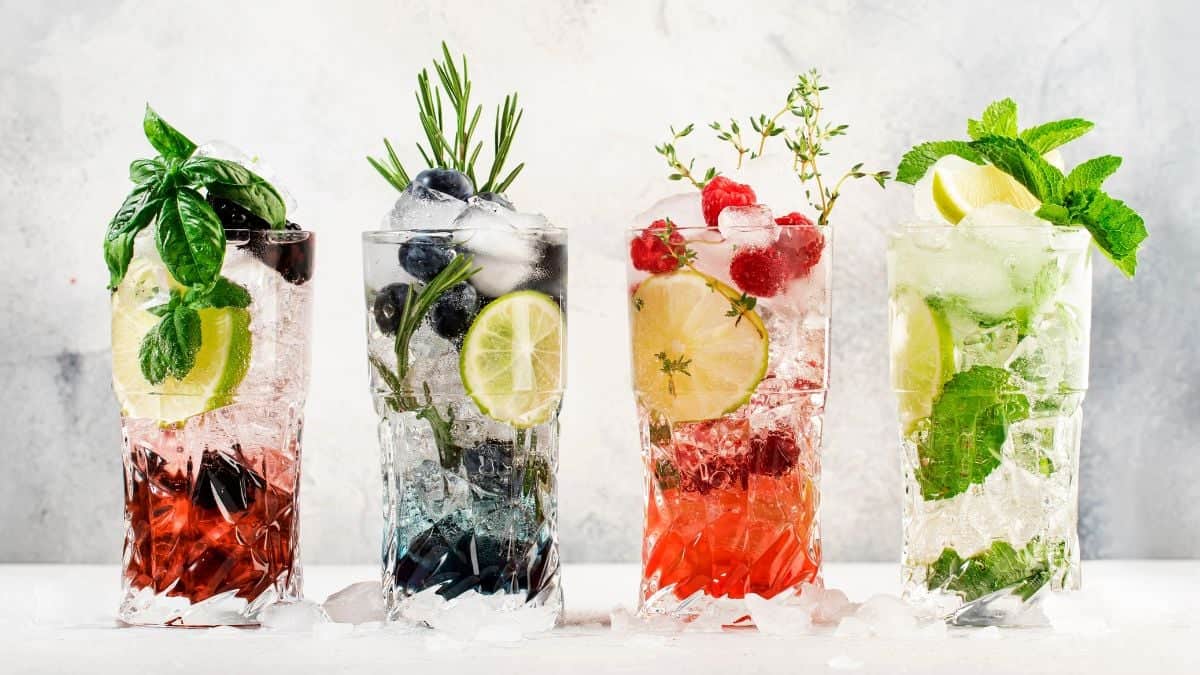 Four colorful cocktails with various garnishes on a light background.