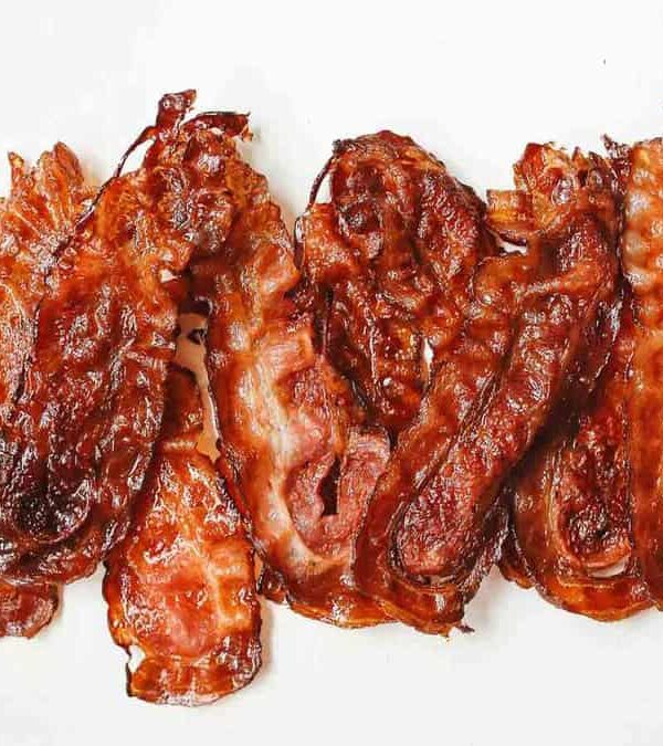 Five strips of crispy bacon arranged side by side on a plain white background.