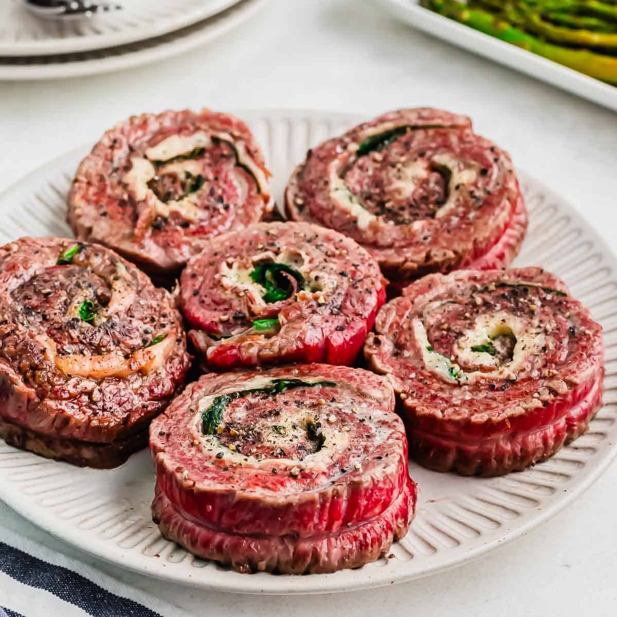 A plate of beef pinwheels filled with herbs and cheese.
