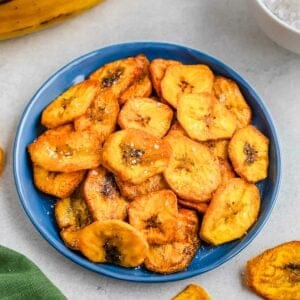 Fried plantain slices in a blue bowl, served on a light background.