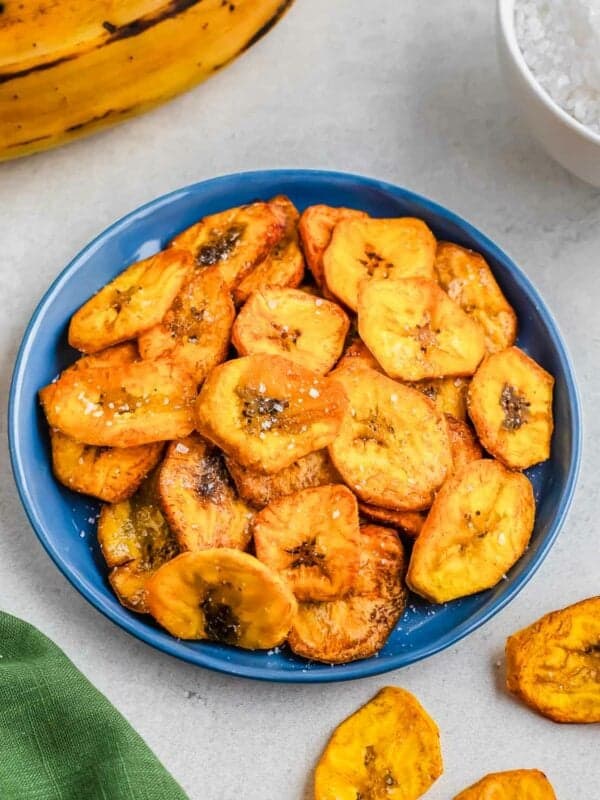 Fried plantain slices in a blue bowl, served on a light background.