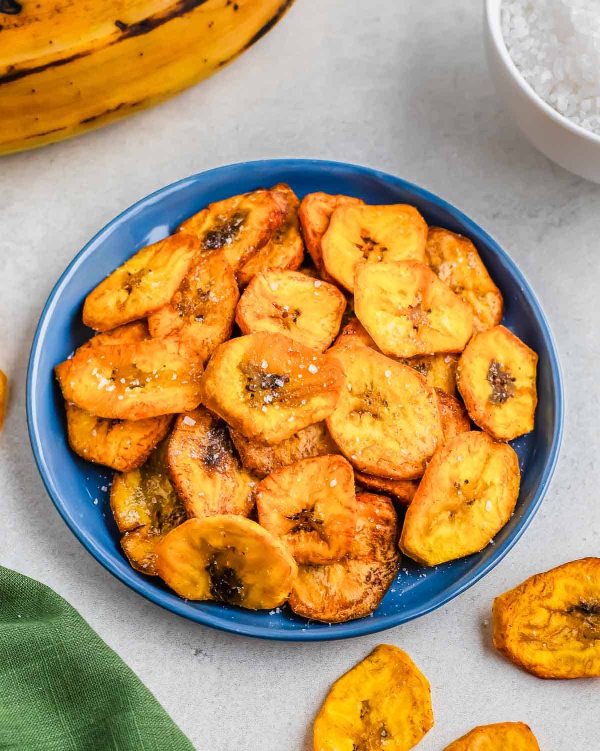 Fried plantain slices in a blue bowl, served on a light background.