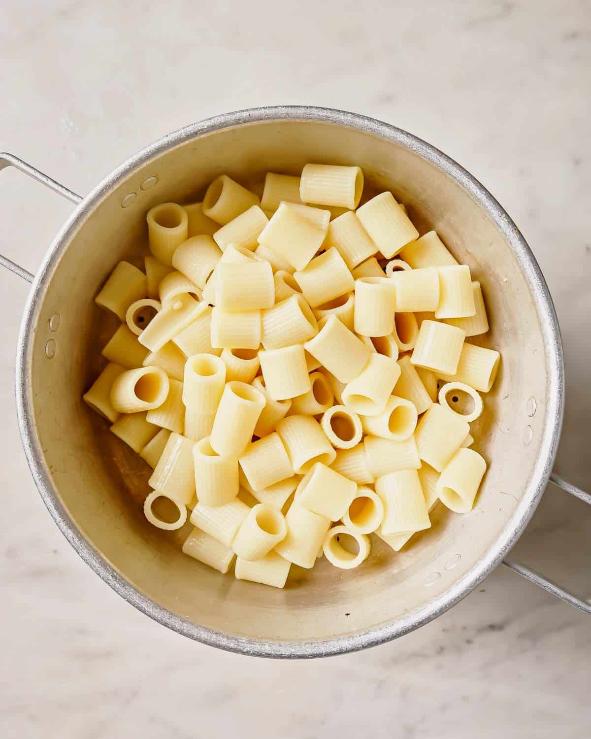 Cooked rigatoni pasta in a strainer.