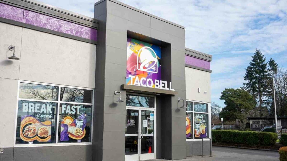 A taco bell restaurant entrance with promotional window graphics advertising breakfast options.