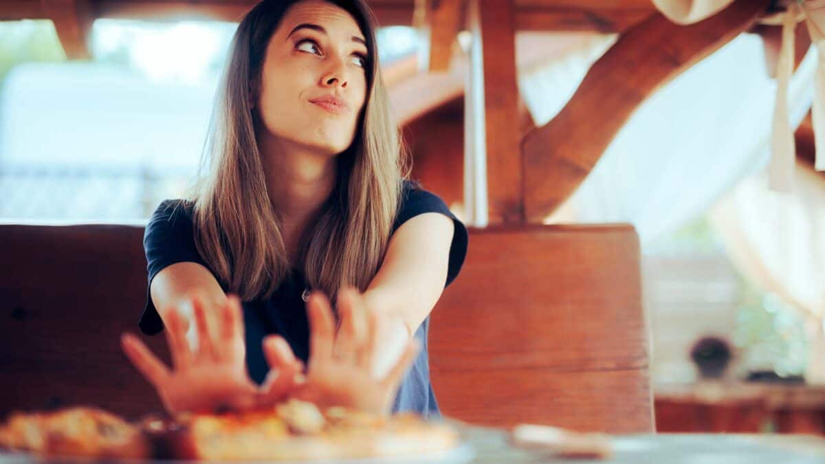 Woman pushing a plate of food away from her.
