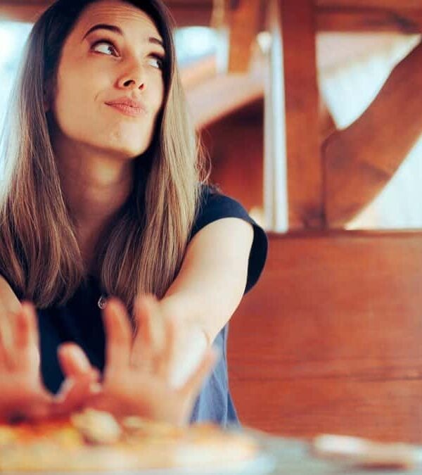 Woman pushing a plate of food away from her.