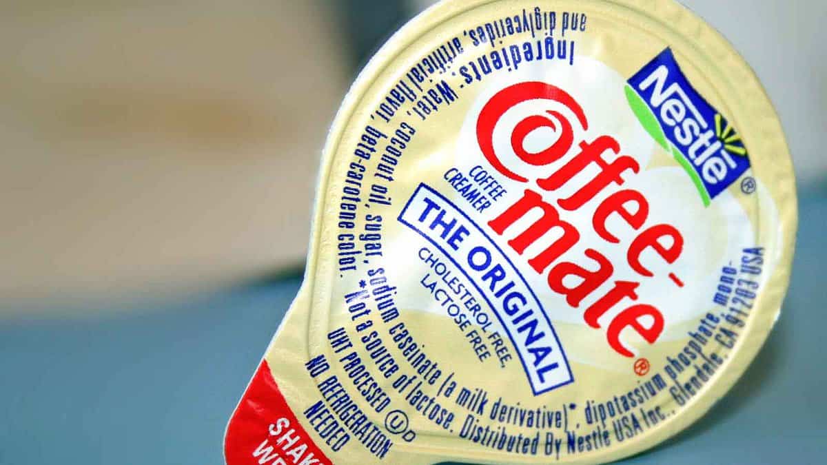 Close-up image of a single-serve Coffee-mate coffee creamer with Nestlé logo, showing "The Original" flavor. The packaging indicates it is cholesterol-free, lactose-free, and contains no trans fat.