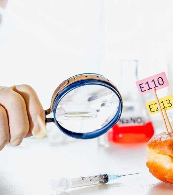 Food scientist with magnifying glass on a donut looking at food additives.