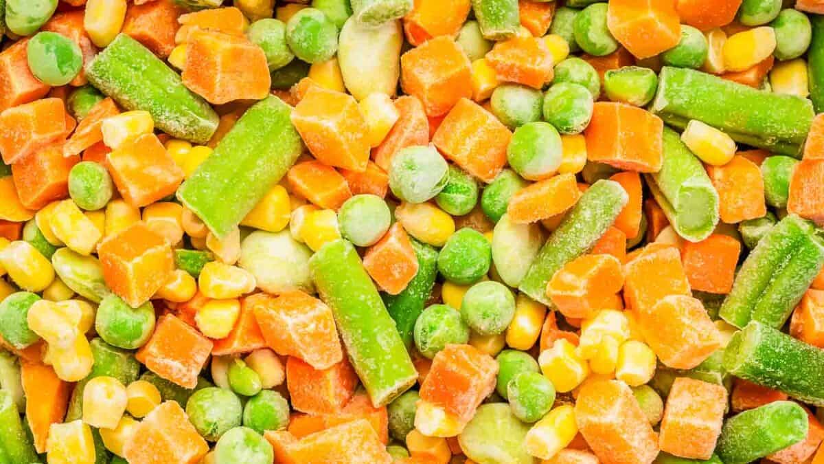 Close-up view of mixed frozen vegetables including carrots, peas, corn, and green beans.