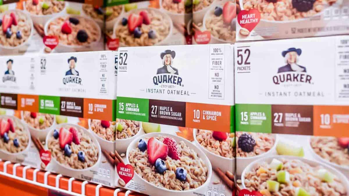 Aisle in a grocery store displaying boxes of quaker instant oatmeal in various flavors.