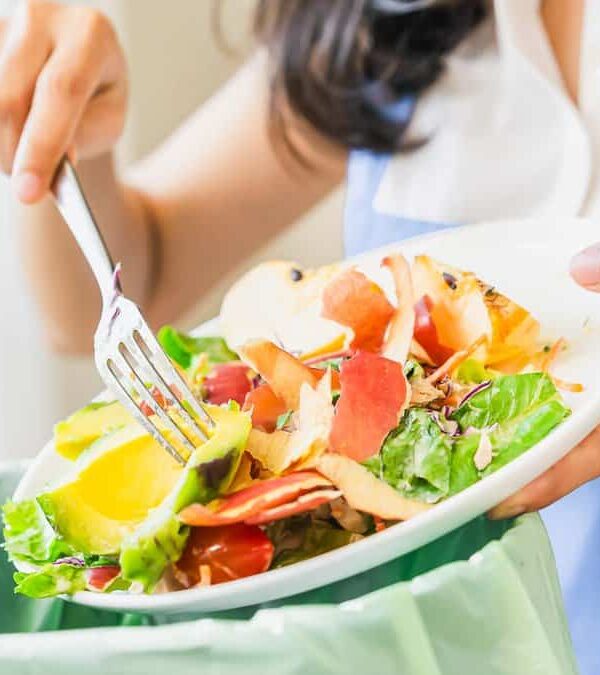 Compost from leftover food asian young housekeeper woman, female hand holding salad bowl use fork scraping waste, rotten vegetable throwing away into garbage, trash or bin.