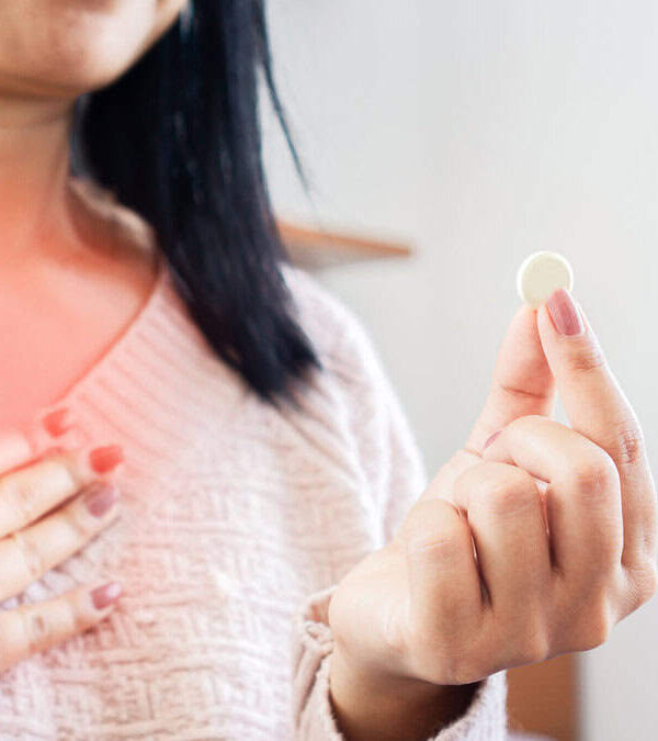 Woman taking medicine for GERD, having problem with heartburn from acid reflux disease, discomfort caused by stomach bloating.