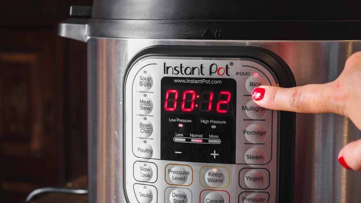 A finger presses the "Rice" button on an Instant Pot with a digital display showing 00:12 in red.