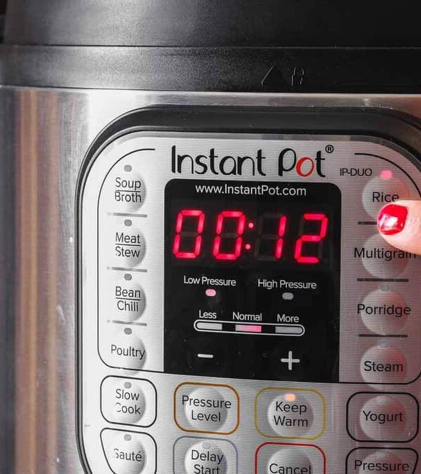 A finger presses the "Rice" button on an Instant Pot with a digital display showing 00:12 in red.