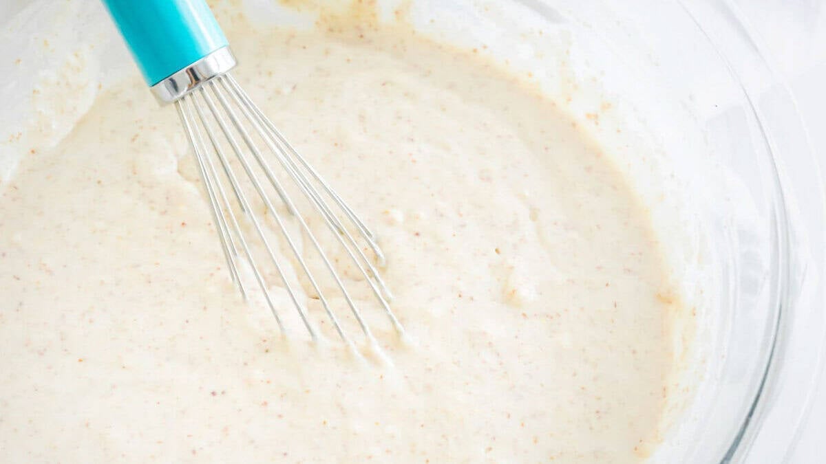 Pancake batter with a blue whisk.