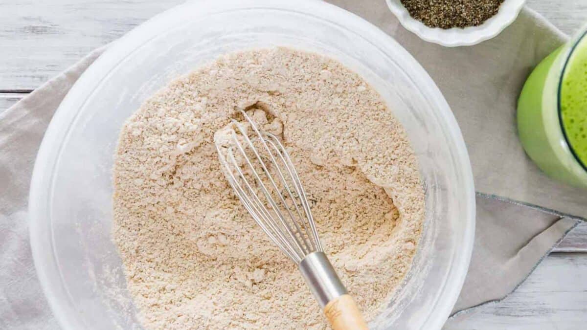 Dry ingredients for pancakes in a bowl with a whisk.