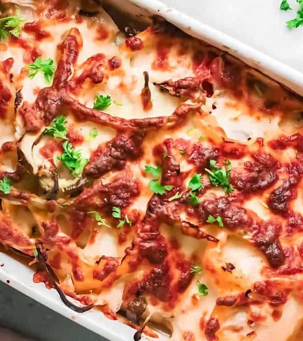 A baked casserole dish featuring lasagna with visible layers of pasta, melted cheese, and a tomato-based sauce, garnished with fresh herbs.