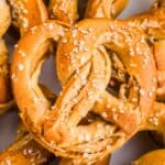 A close-up of several freshly baked soft GF pretzels sprinkled with coarse salt.