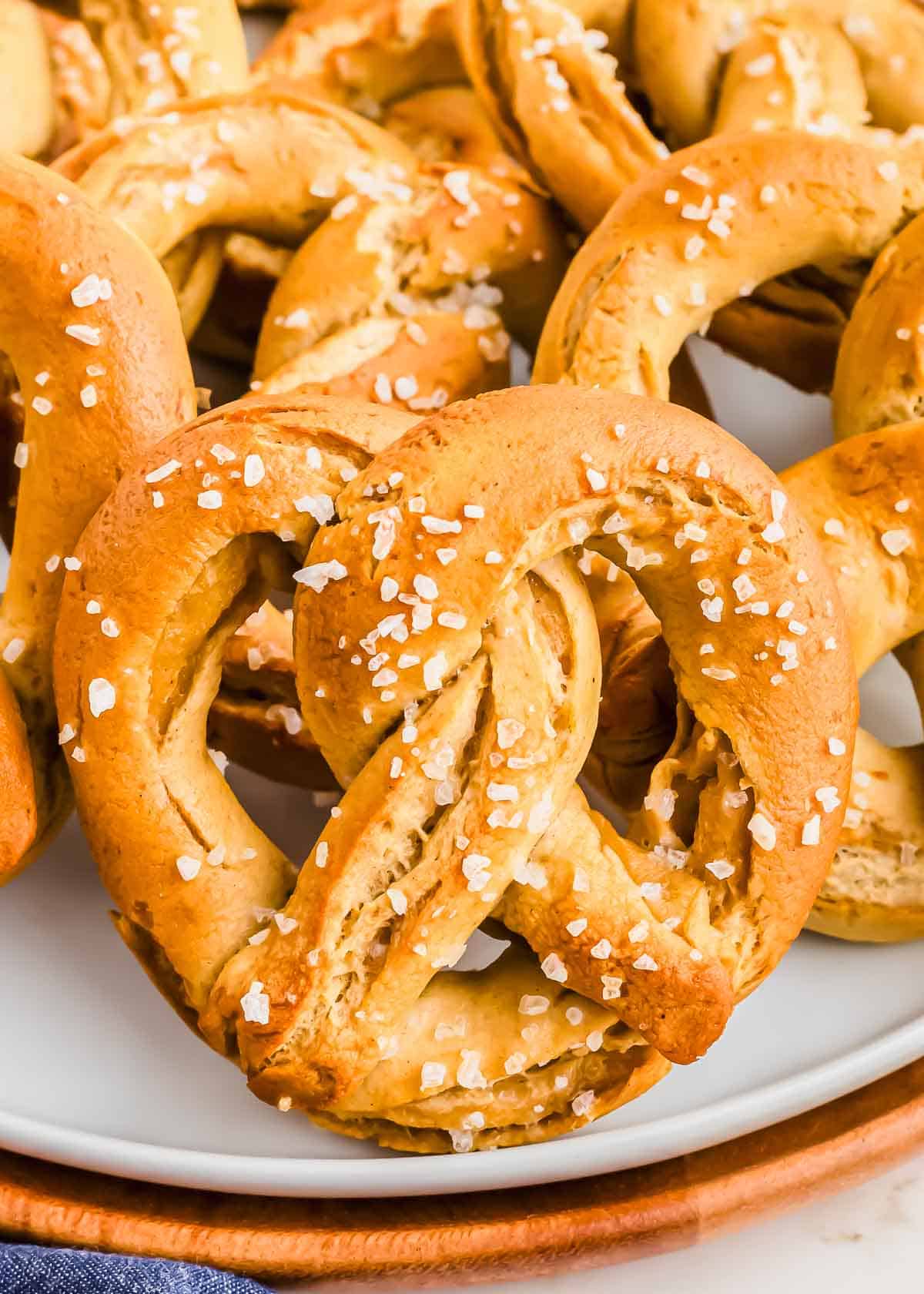 A plate filled with freshly baked soft pretzels topped with coarse salt.