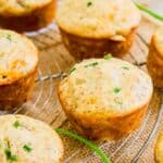 Freshly baked savory muffins cooling on a wire rack, garnished with green herbs.